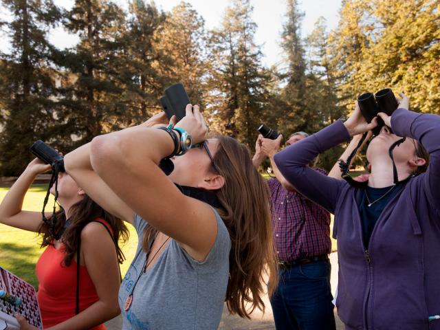 Students birdwatching with binoculars in the Arboretum