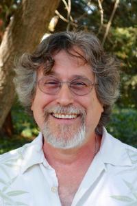 A smiling man wearing a light-colored shirt